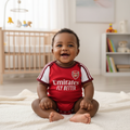 Nigerian baby wearing red & white football romper bodysuit with Emirates trim lifestyle shot