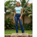 Nigerian female model wearing women's navy blue crossover waistband straight-leg denim jeans, garden setting