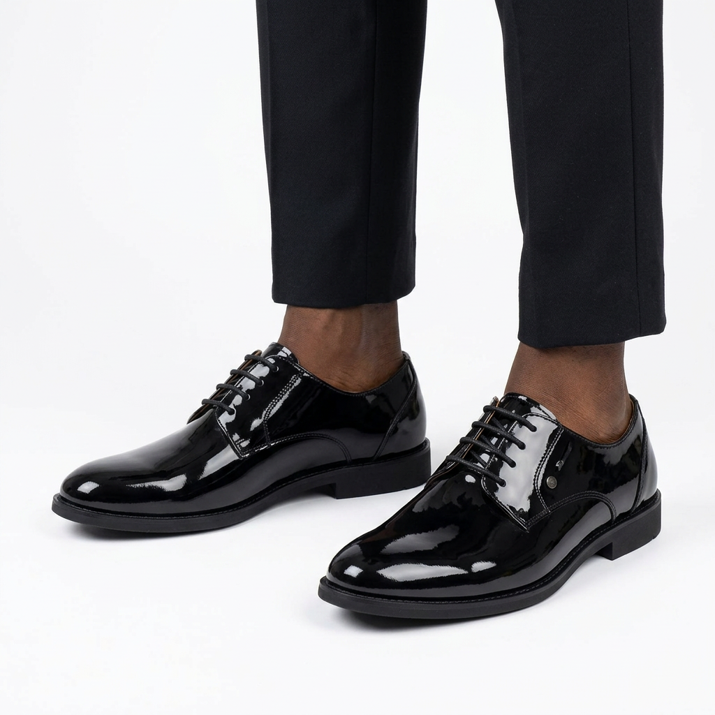 Black male model wearing both high-shine black derby shoes on white