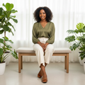 Nigerian female model seated wearing tan croc-embossed patent ballet flats with strap buckle detail