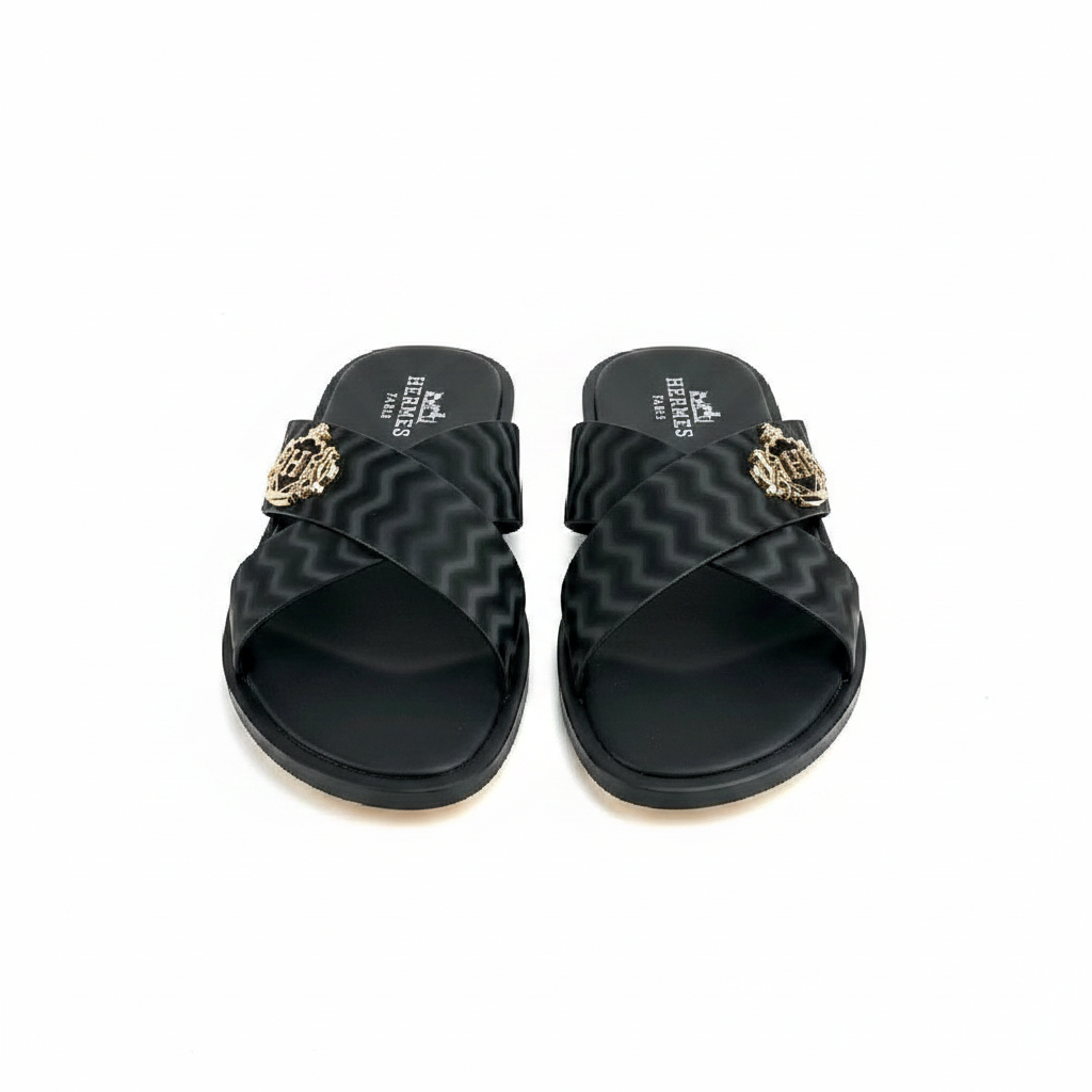 Men's black wave ripple embossed leather cross-strap slide sandals with gold crest shield badge, tan leather outsole, ghost mannequin pair view on white background