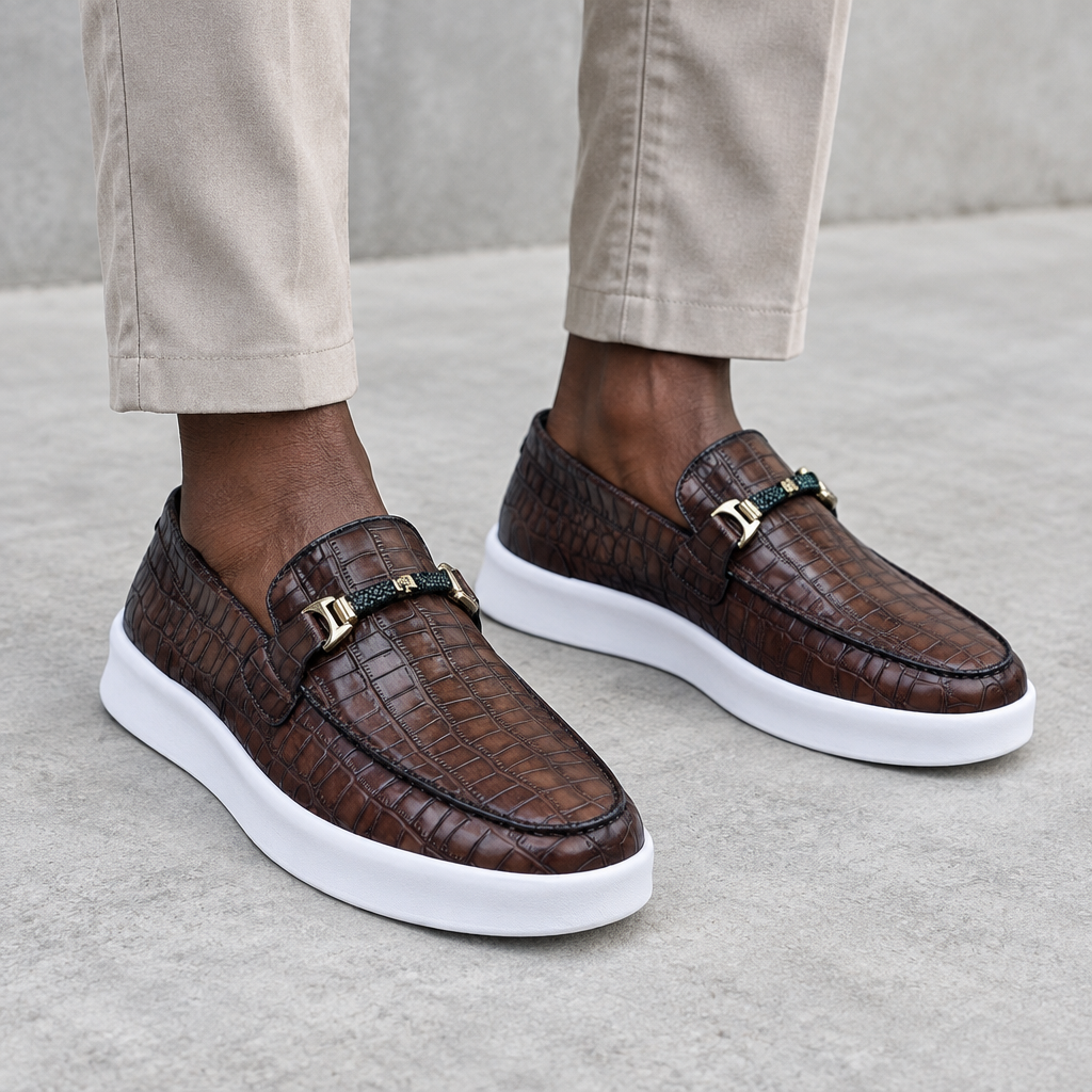 Dark brown embossed loafers with gold-tone hardware, worn on both feet