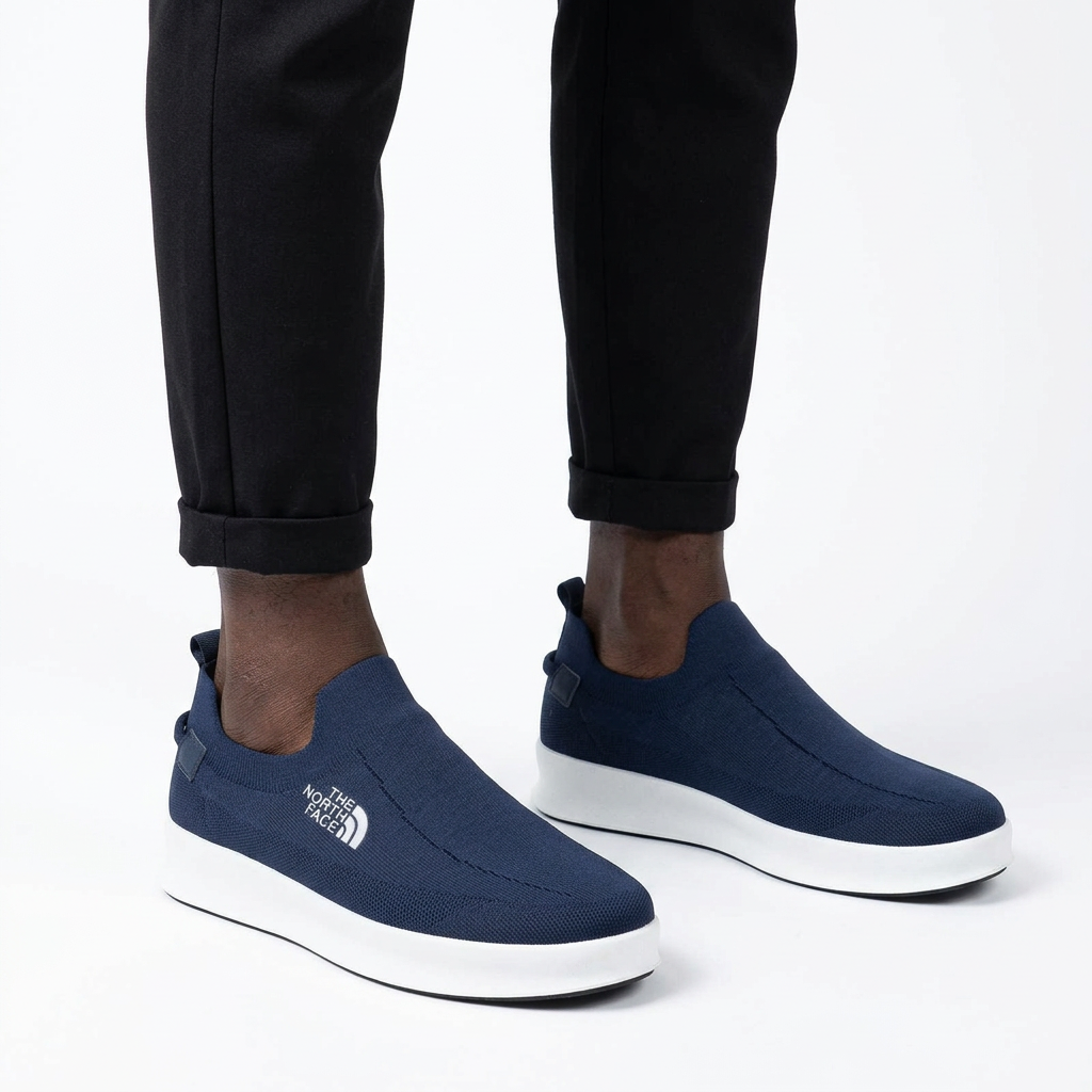 Navy white-sole slip-on sneakers properly worn on both feet