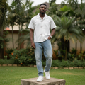 Nigerian male model wearing white camp collar hook-clasp shirt – full body lifestyle shot