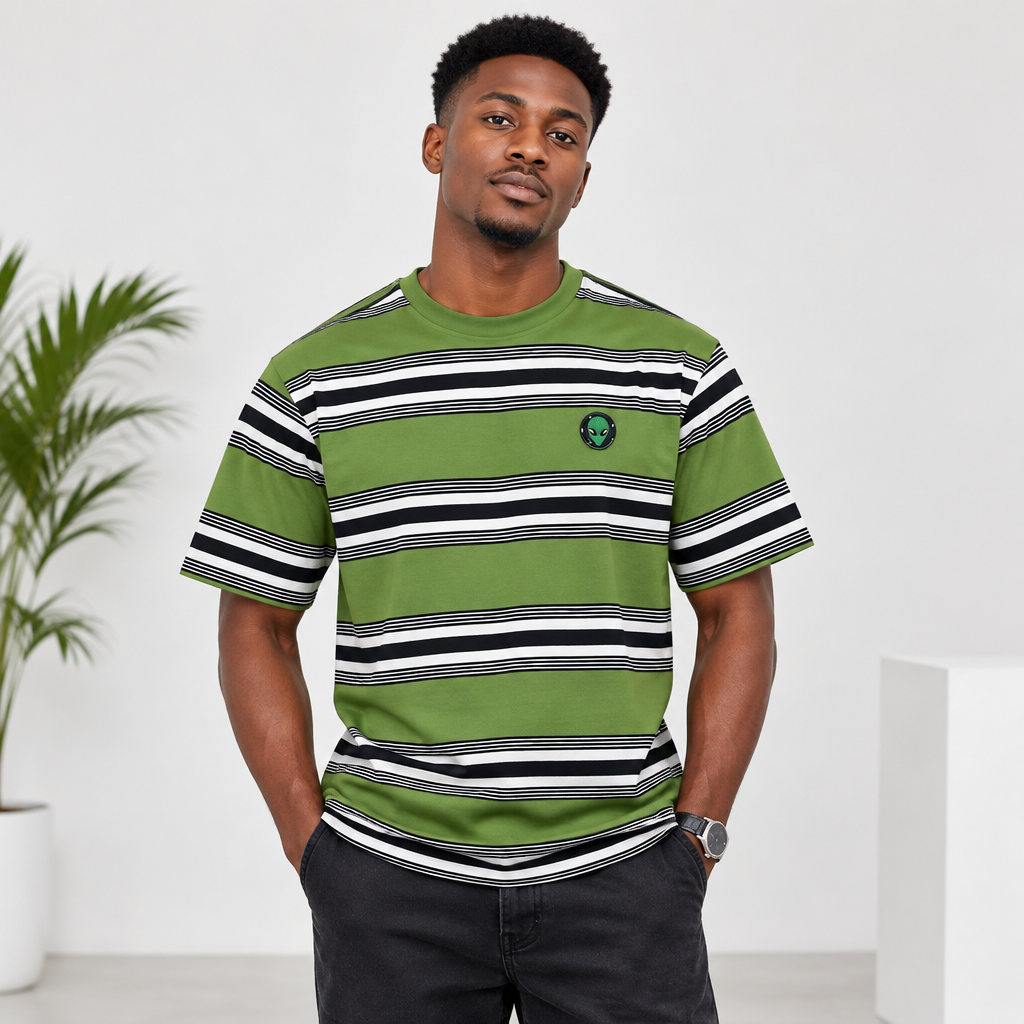 Young Black Nigerian man wearing olive green striped crew neck tee with alien badge