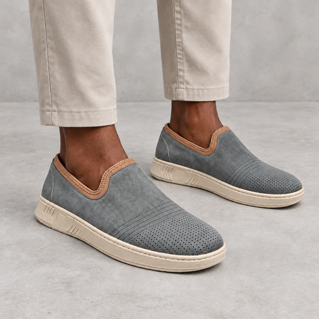 Men's grey slip-on sneakers with tan collar trim worn on both feet