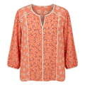 Coral floral split-neck blouse with cream piping on an invisible mannequin