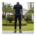 Nigerian male model wearing black leather cross-strap slide sandals with dark navy trousers in garden setting