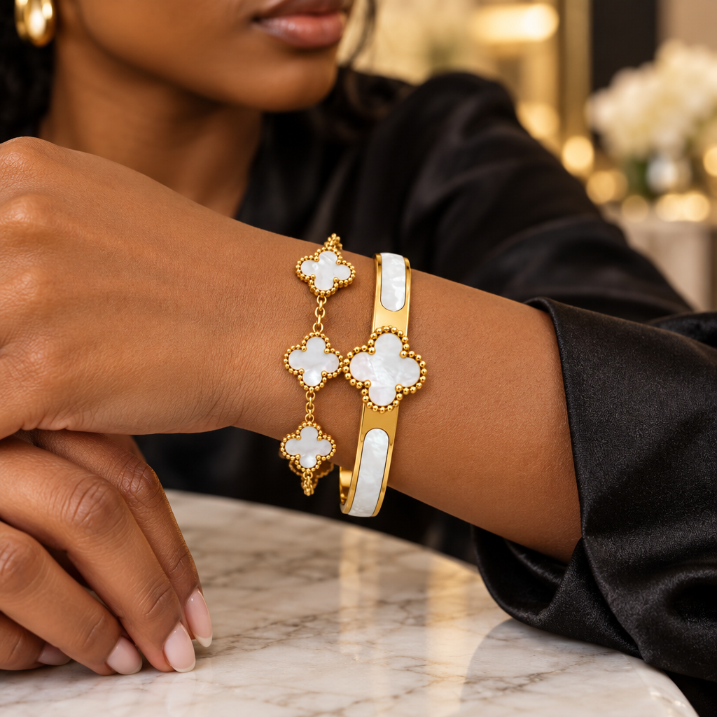 Woman wearing gold pearl clover bangle and chain bracelet stacked on wrist