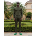 Nigerian male model wearing green embossed cross-strap slide sandals with olive trousers in garden setting