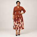 Black Nigerian model wearing a rust pleated gown with floral waist accents