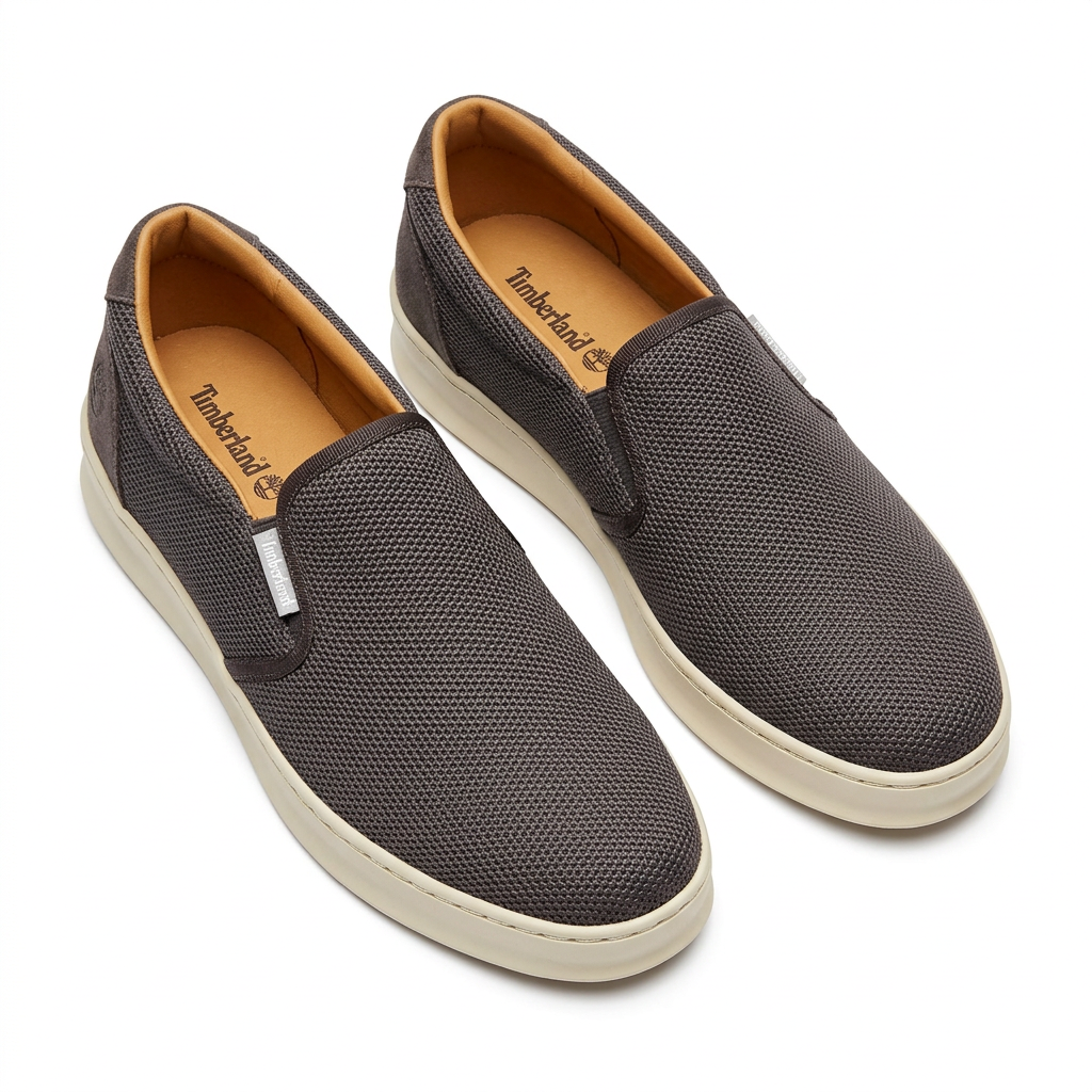 Pair of charcoal grey woven slip on sneakers with cream soles on white background