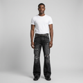 Young Nigerian man wearing washed-black distressed flared jeans in light grey studio