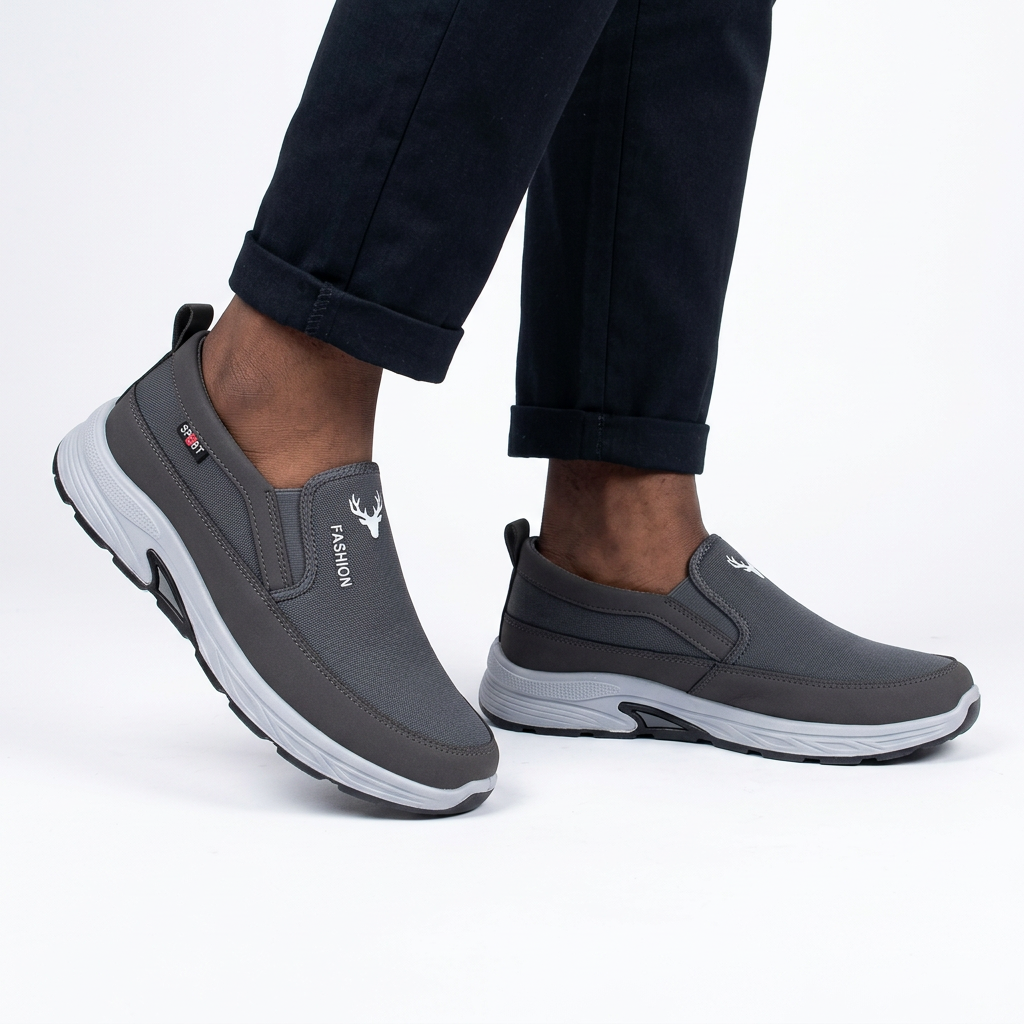 Charcoal grey slip-on shoes worn on both feet by a Black male model on white
