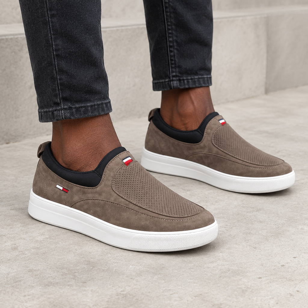 Taupe perforated slip-on shoes worn on both feet
