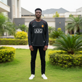Black long-sleeve retro football jersey with red piping and AIG sponsor — Nigerian male model front view
