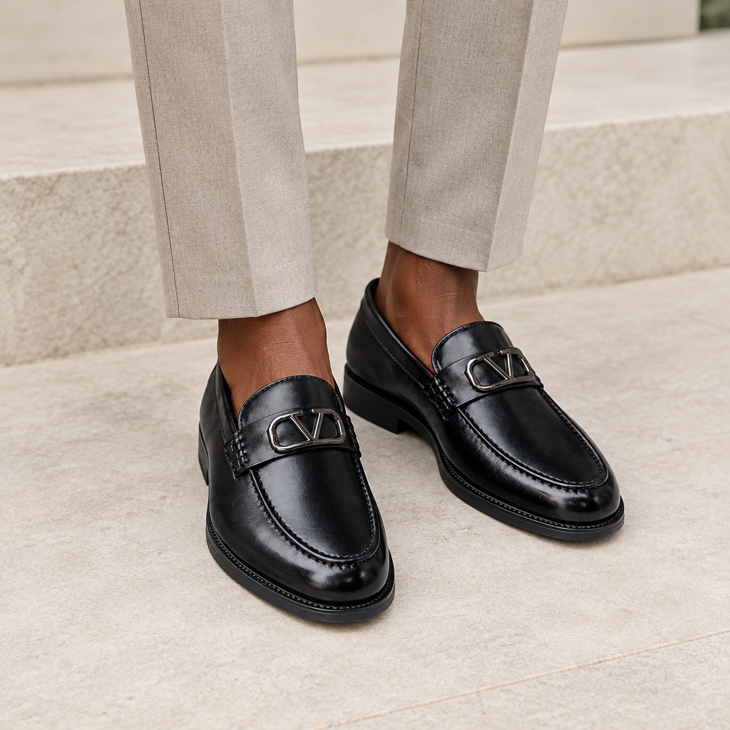 Black model wearing black men's loafers with polished metal buckle detail