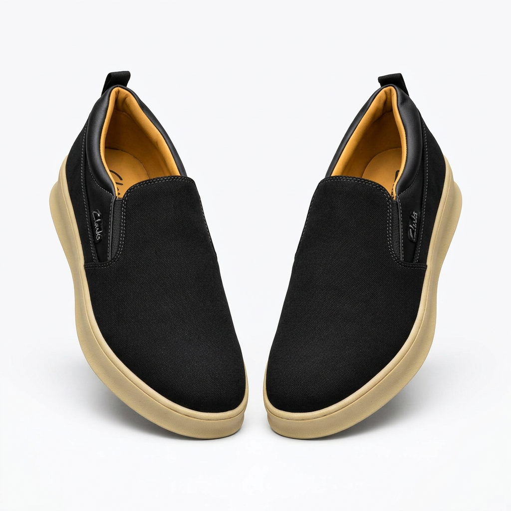 Pair of matte black men's slip-on shoes with cream soles on white