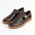 Pair of dark brown perforated slip on shoes with tan soles on white background
