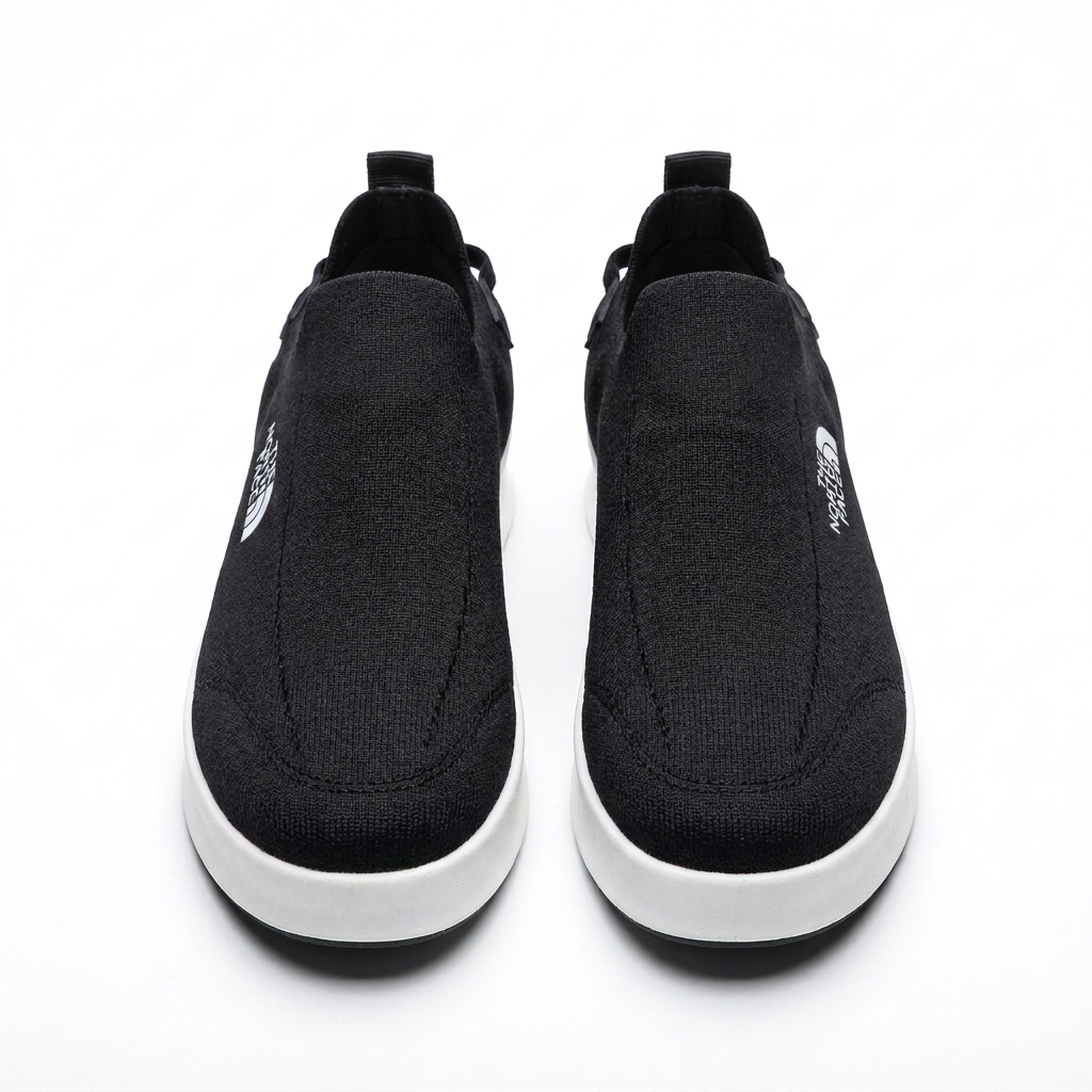 Straight-on black slip-on sneakers with textured uppers and white soles