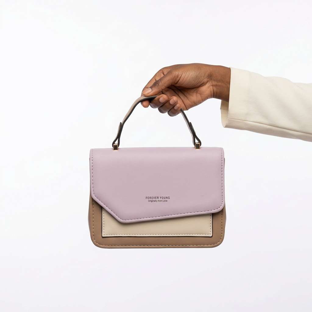 Black adult woman’s hand holding a lilac and taupe handbag on white