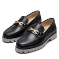 Pair of black loafers with textured gold-tone hardware and grey lug soles on white