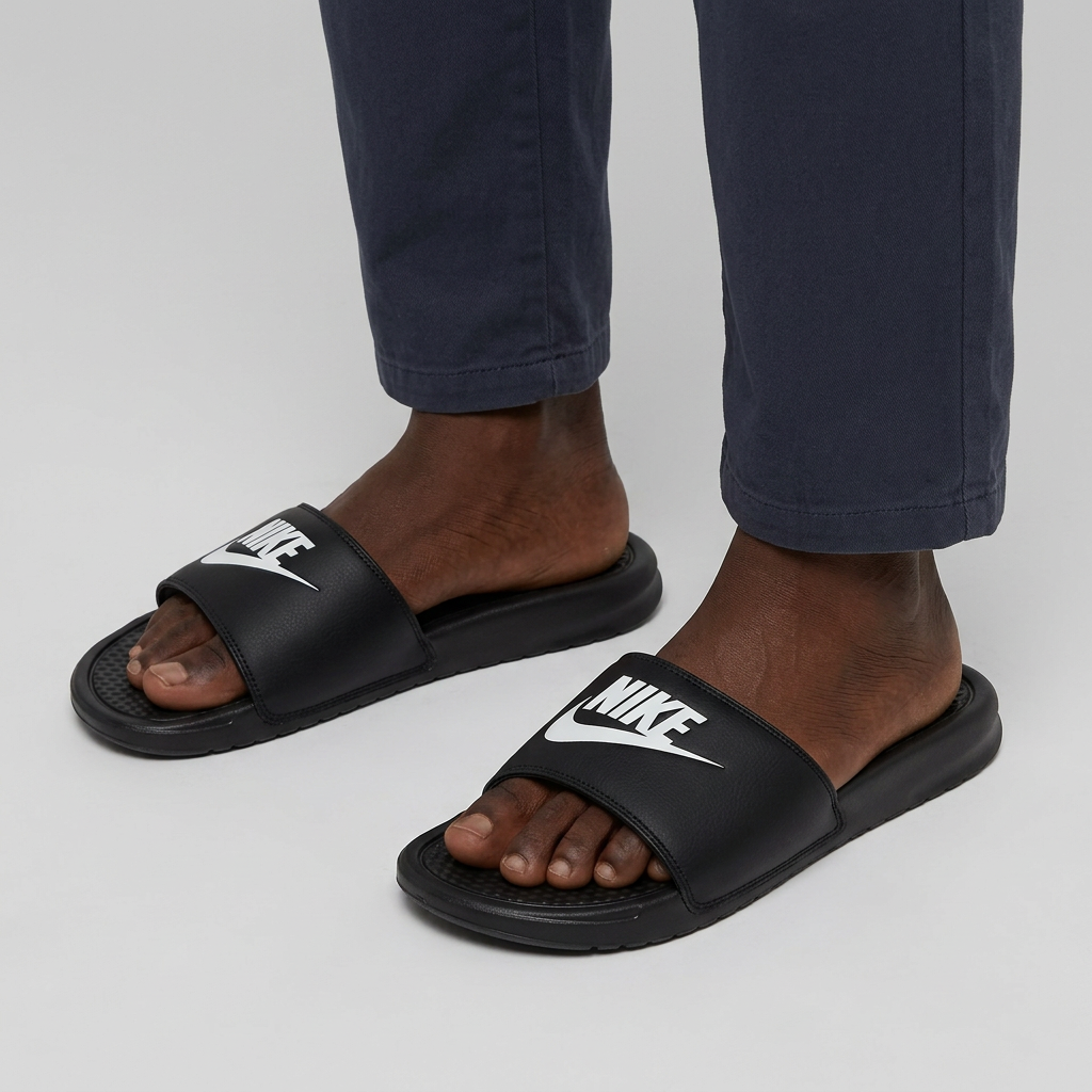 Both feet of Nigerian male model wearing black graphic-strap slides