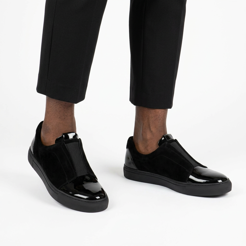 Both black glossy toe-cap slip-ons worn with black trousers on white