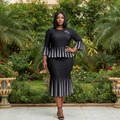 Nigerian female model wearing black pleated peplum blouse and midi skirt co-ord set in garden setting