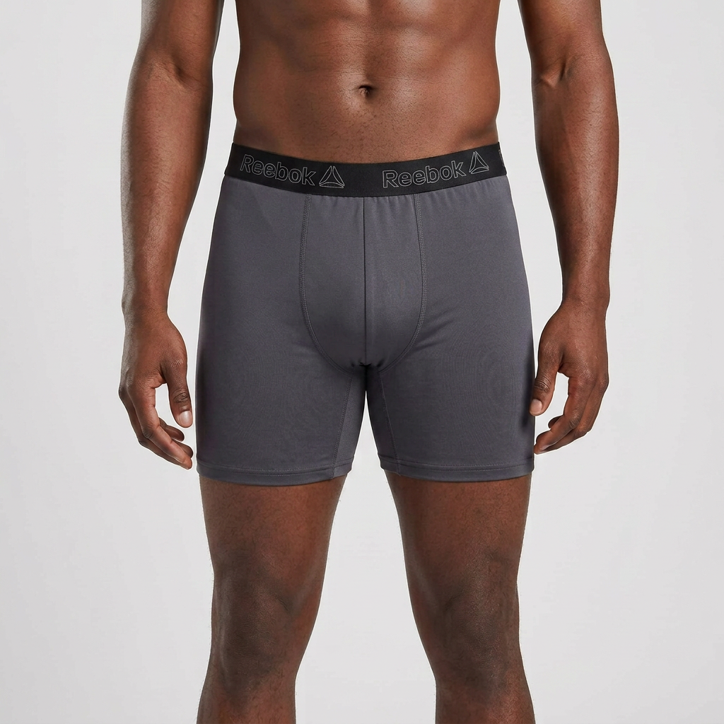 Single male model wearing charcoal boxer briefs with black outlined-brand waistband on plain background