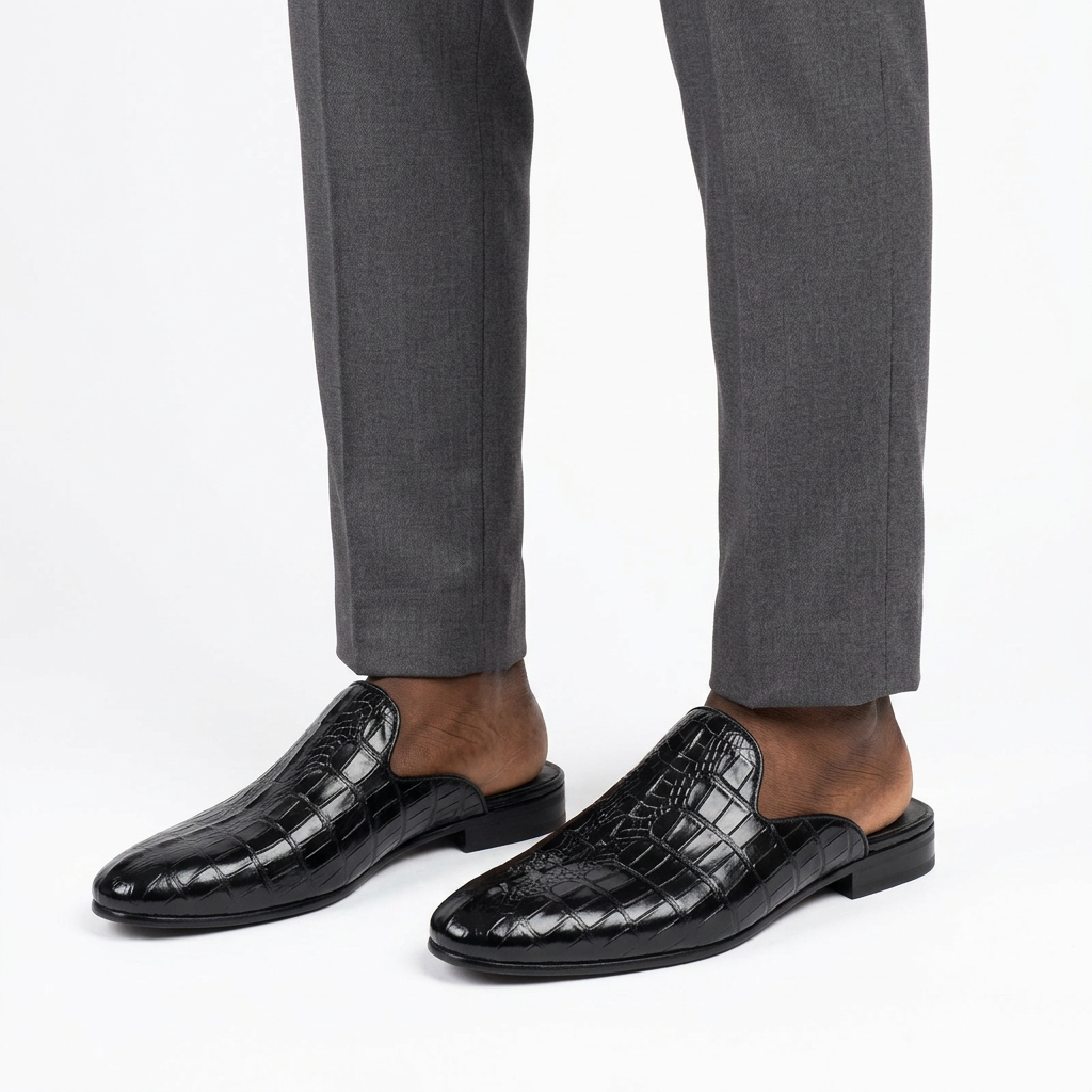 Men’s black crocodile-textured mule shoes worn with tailored trousers