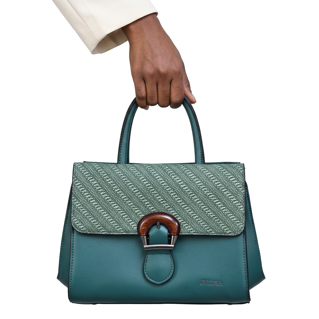 Black adult woman’s hand holding a teal patterned-flap handbag on white