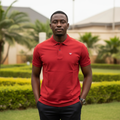 Nigerian male model wearing men's red polo shirt with branded shoulder tape, garden setting
