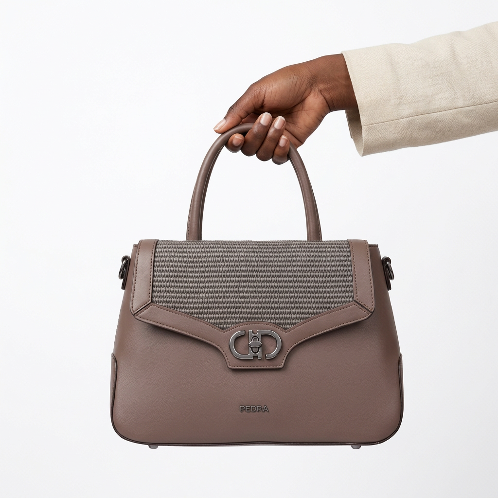 Black adult woman’s hand holding a taupe-brown woven-panel handbag on white