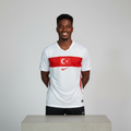 Nigerian male model wearing white football jersey with red chest band on concrete plinth