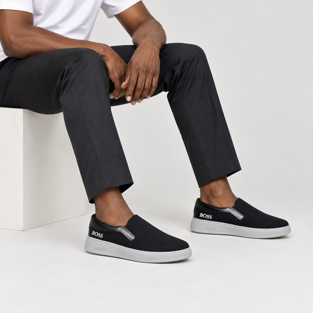 Leg-focused model view of black slip-on sneakers with dark trousers