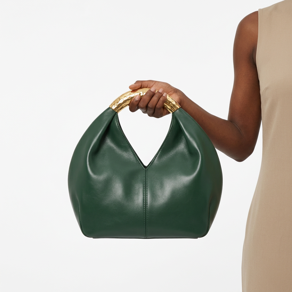 Deep-green rounded handbag without label held by one hand at its gold-tone handle
