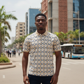 Young Nigerian male model wearing cream diamond print polo shirt, front view, Nigerian urban background