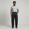 Full-body male model wearing black asymmetric-waist trousers