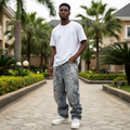 Nigerian male model wearing dark grey paint splatter chain hardware extreme distressed baggy jeans