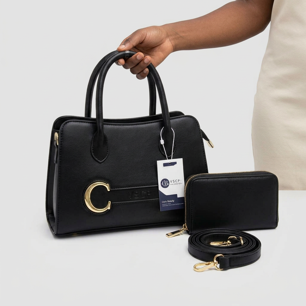 Hand holding black buckle-detail handbag with matching wallet and strap