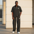 Male model wearing black white pinstripe gothic logo polo and trouser two-piece set