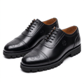 Pair of black cap-toe brogue lace-ups with black lug soles on white