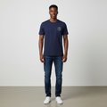 Young Nigerian male wearing deep navy Outfitters Spirit Within circular badge graphic crew neck tee