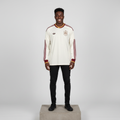 Nigerian male model wearing cream maroon gold long sleeve football jersey on concrete plinth