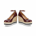 Pair of burgundy croc-embossed patent leather ankle-strap espadrille wedge pumps with striped platform sole on white background