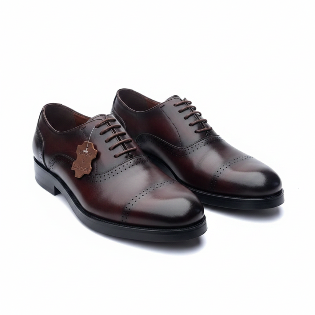 Pair of burgundy leather cap-toe oxford brogues on a white background