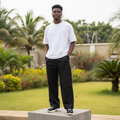 Nigerian male model wearing black wide-leg jogger pants with rivet detail streetwear outdoor
