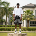 Nigerian male model wearing men's black graffiti tag print clasp hardware denim shorts streetwear style