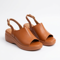 Pair of caramel-tan open-toe slingback wedge sandals on white